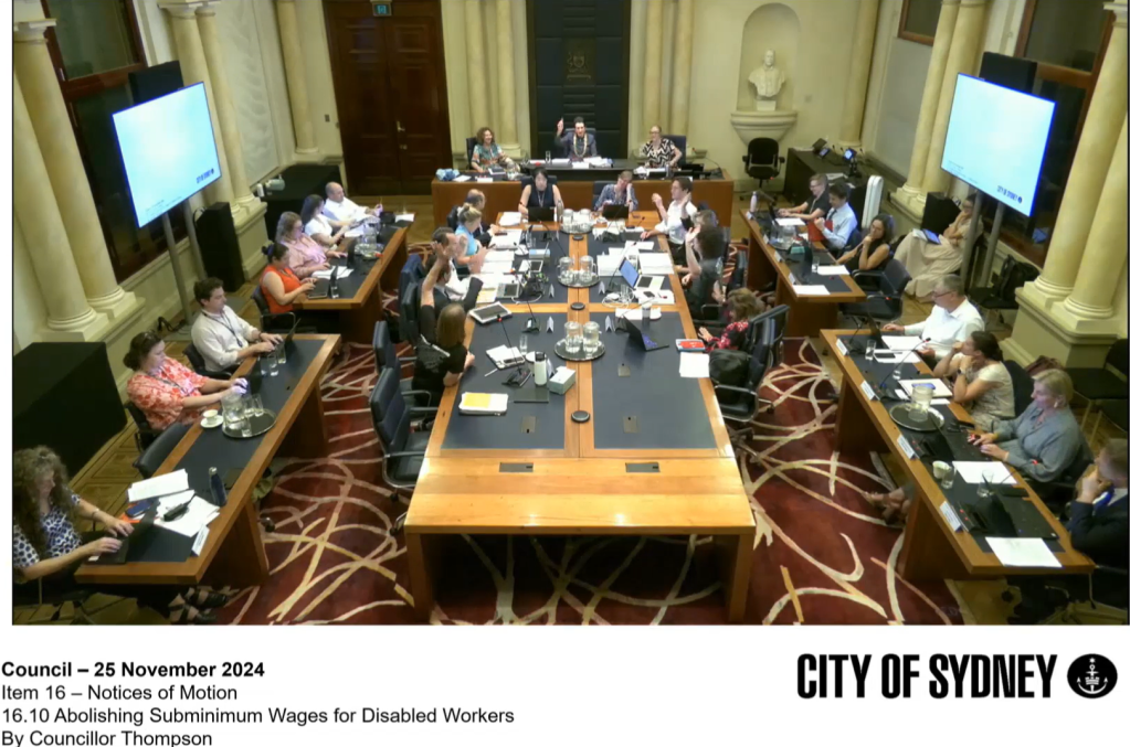 The City of Sydney Council. The text reads "Council - 26 November 2024. Item 16 - Notices of Motion. 16.19 Abolishing Subminimum Wages for Disabled Workers. By Councillor Thompson." All Councillors are raising their hands in support of the motion.